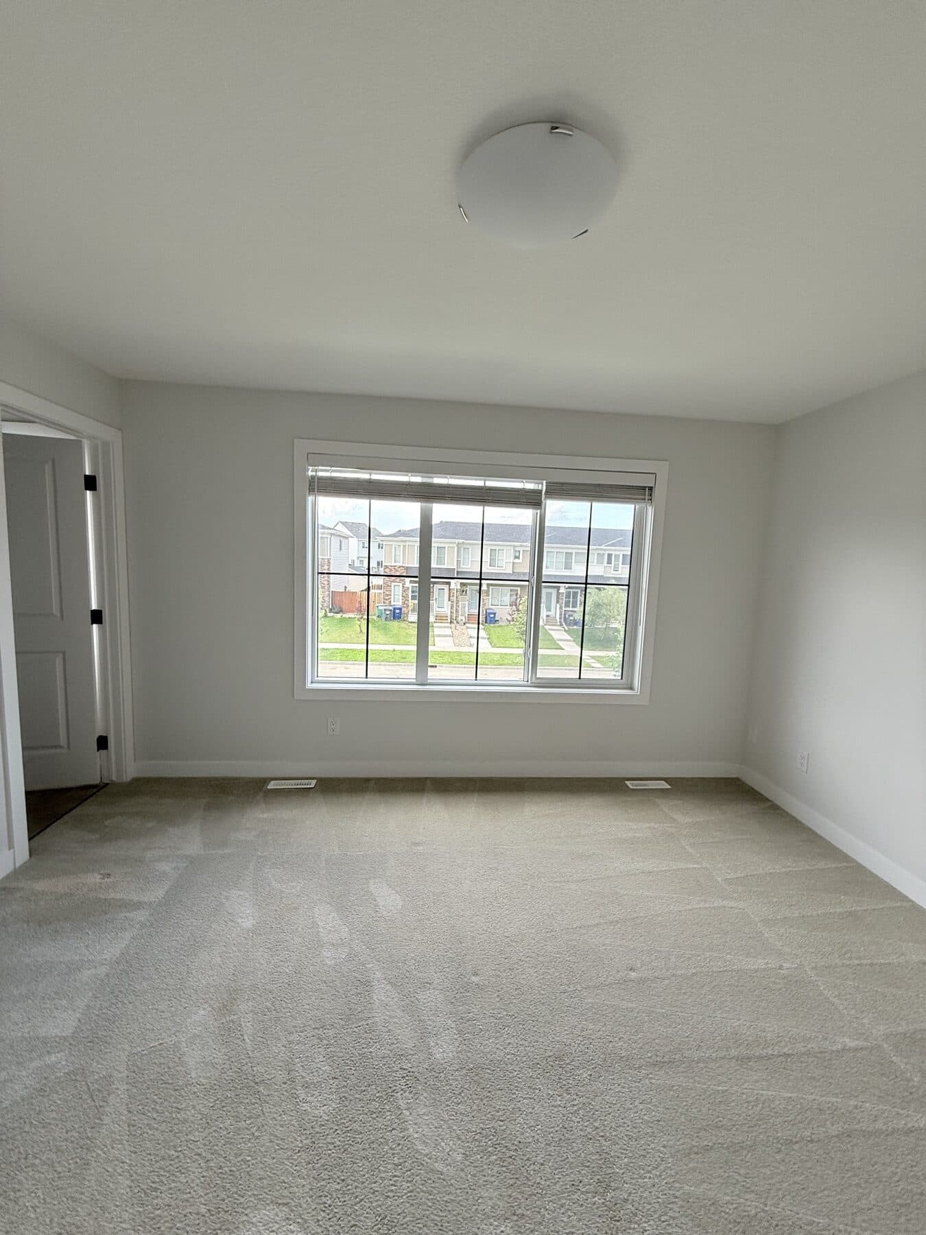 Freshly cleaned living room with visible carpet lines and a bright window