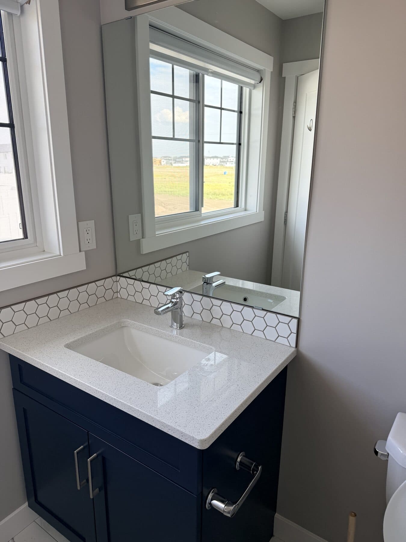 Polished bathroom vanity with a clean sink, mirror, counter, and dark blue cabinets