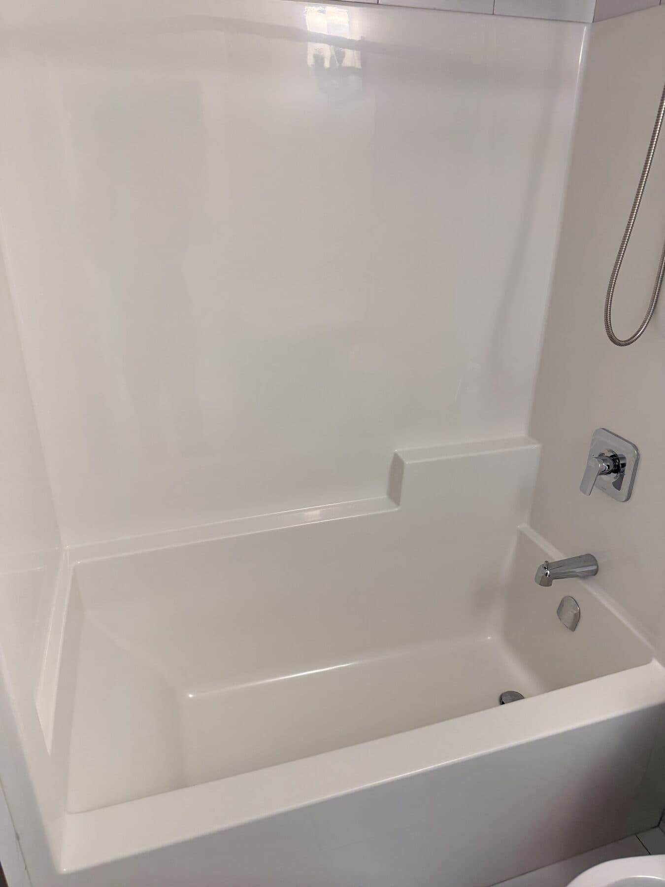 Clean white bathtub and surround with polished fixtures